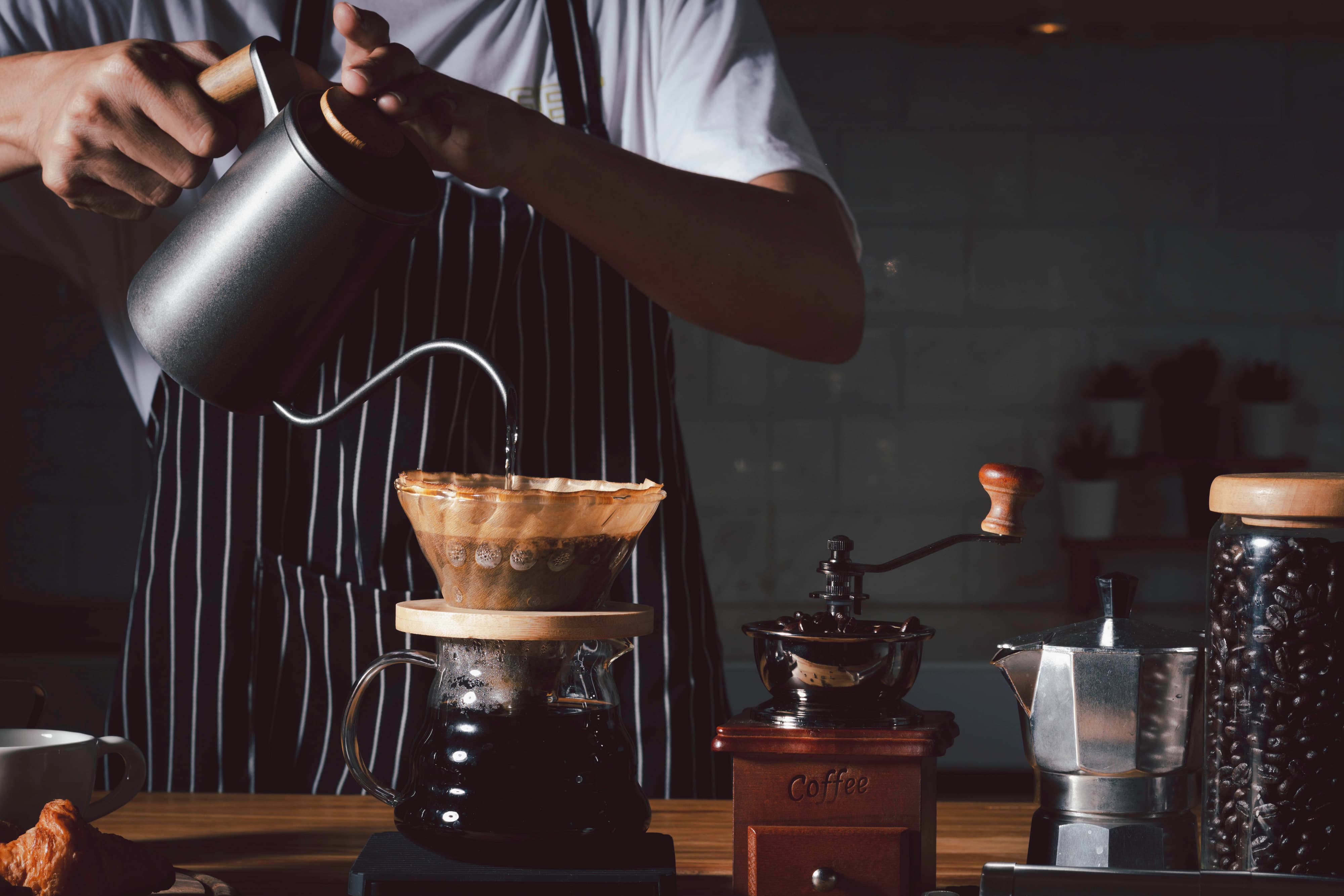 Barista gießt heißes Wasser in Filter bei Pour Over Kaffeezubereitung.