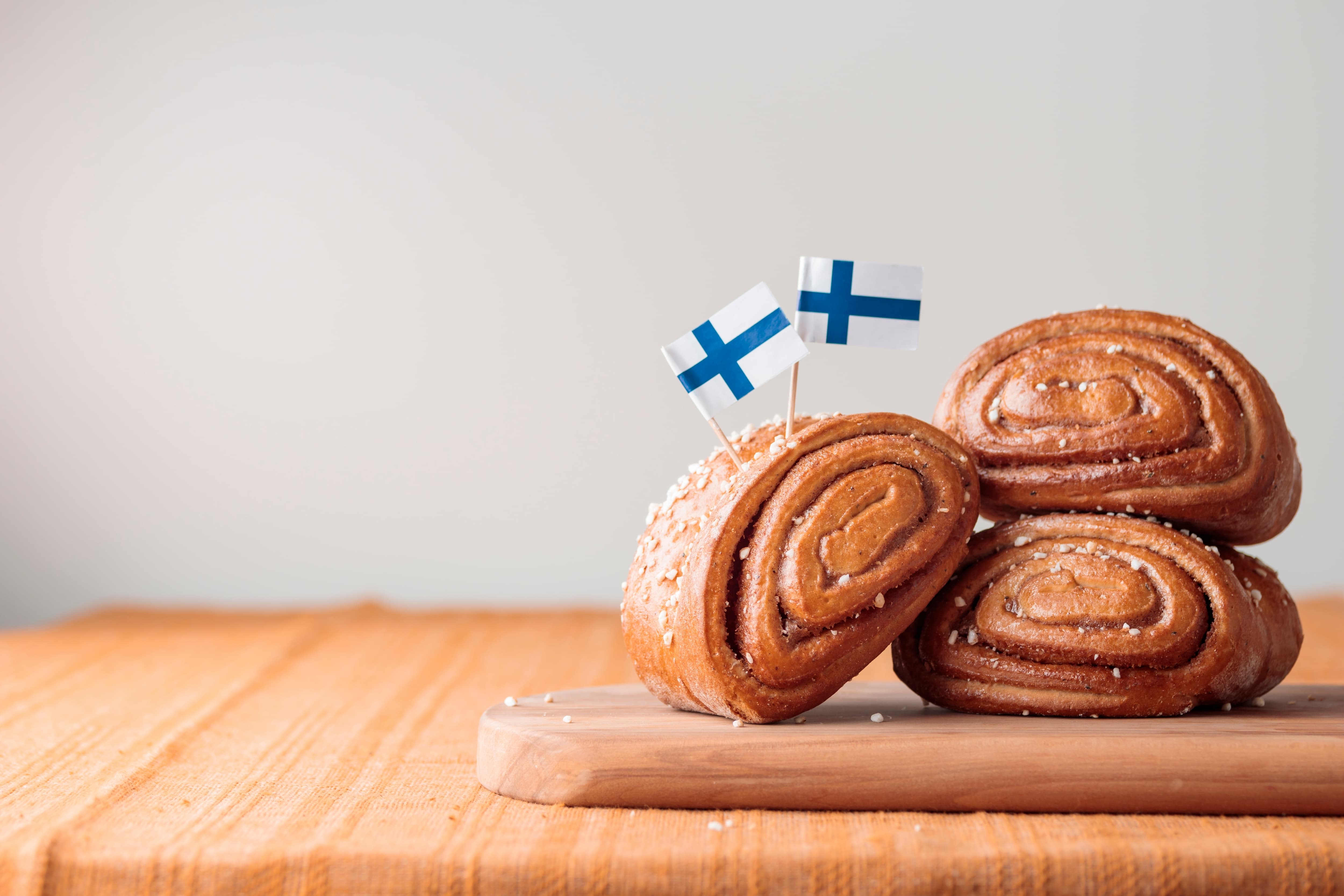 Zimtschnecken dekoriert mit finnischen Flaggen auf einem Holztisch.