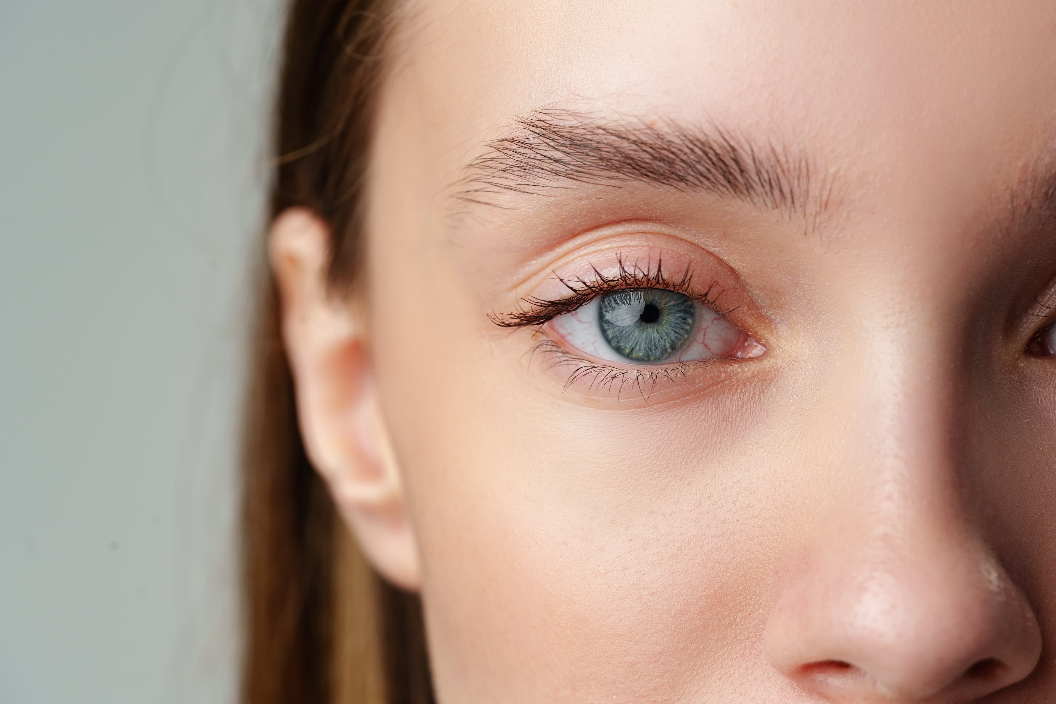 Nahaufnahme eines menschlichen Auges mit blauer Iris und sichtbaren Wimpern.