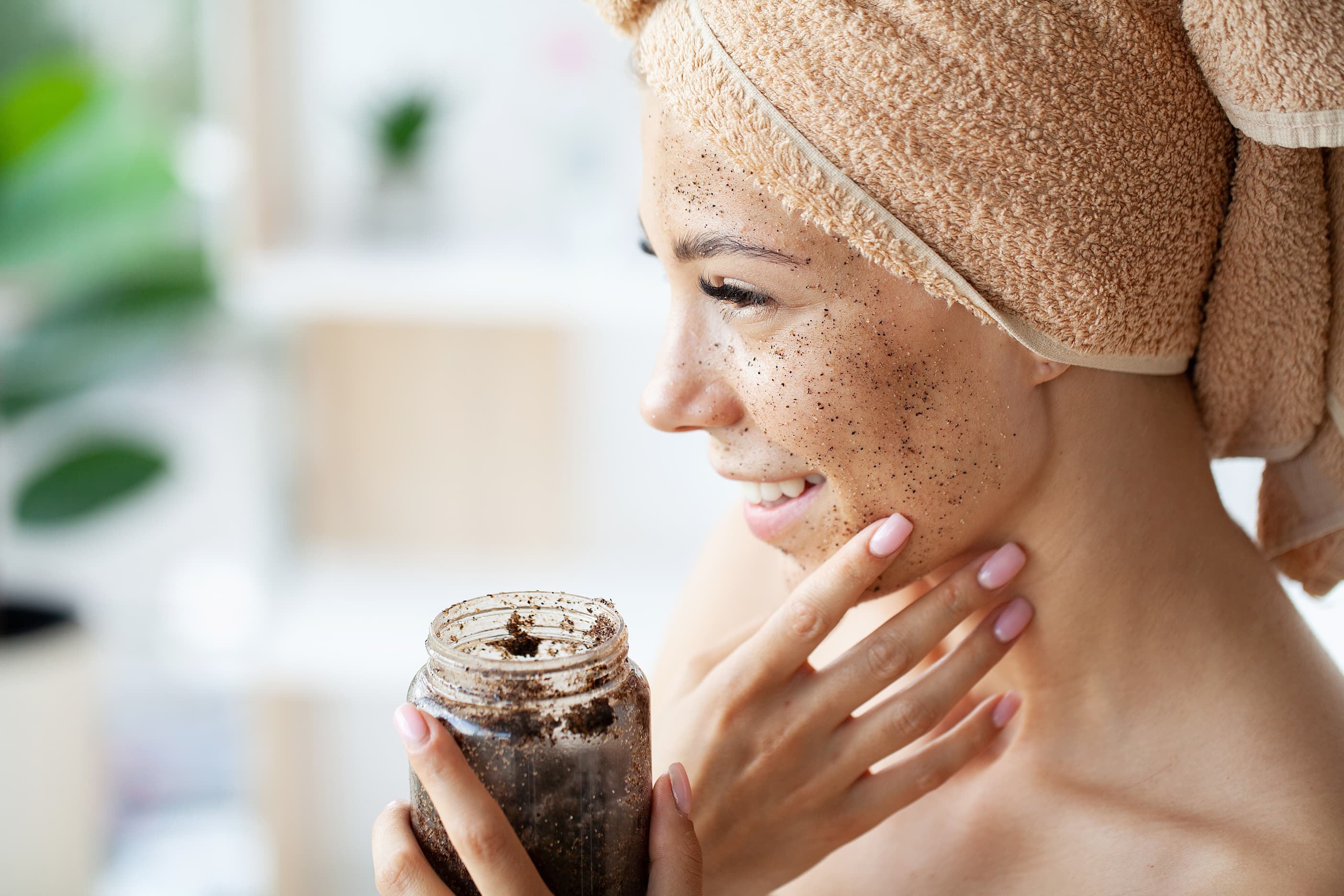 Frau trägt Kaffeepeeling im Gesicht auf, Hautpflege mit Naturkosmetik.